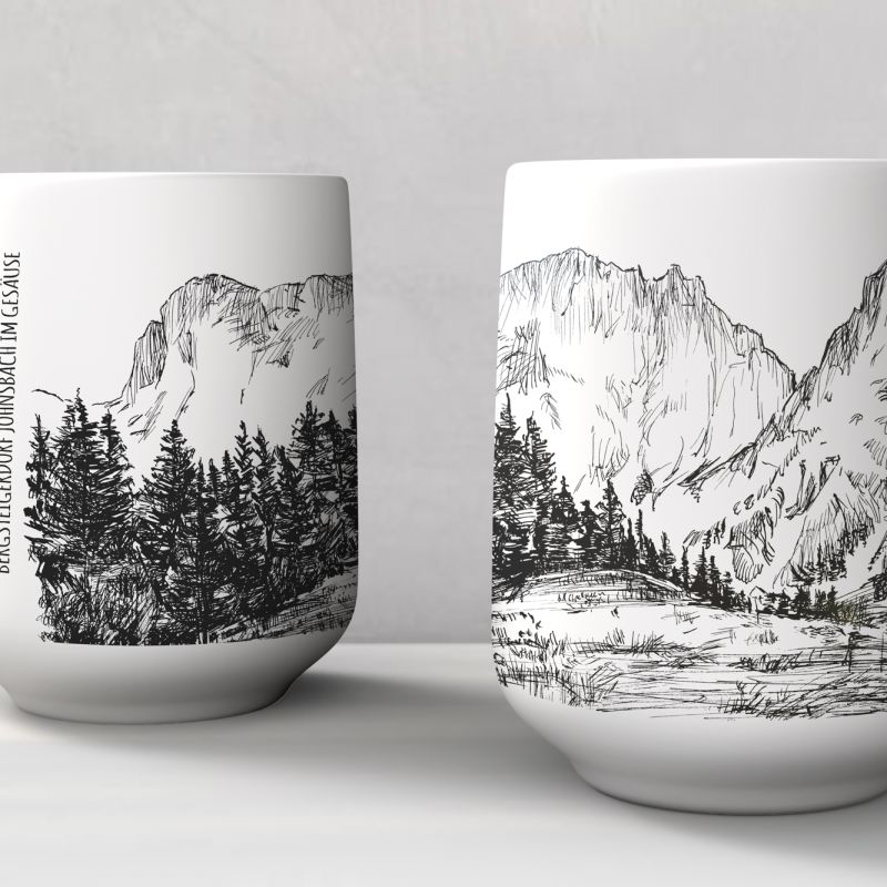 Pair of white mugs printed with mountain and forest landscape artworks