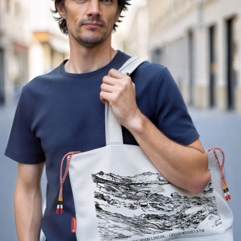 Man carrying an illustrated fabric shoulder bag over a navy T-shirt