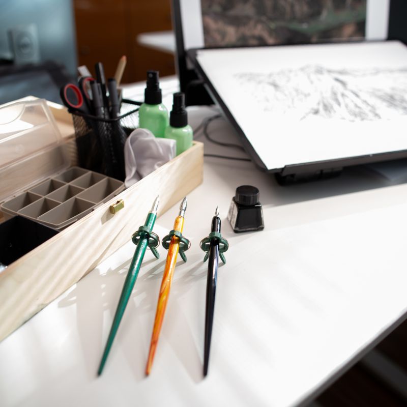 Drawing studio worktable with pens, ink bottles and tools used to create Alpine landscape art