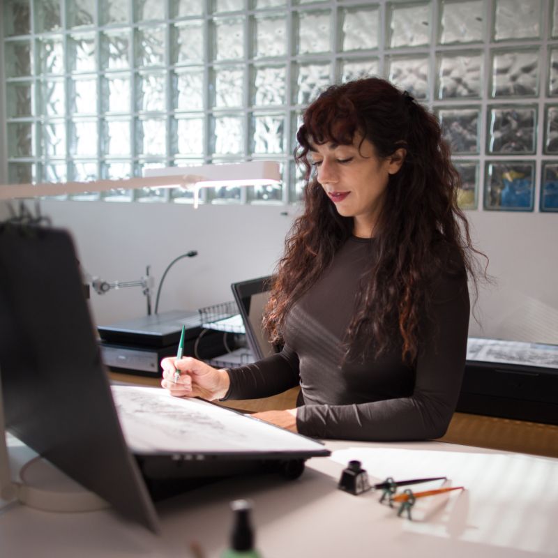Carmesine artist drawing an Alpine landscape illustration in the studio