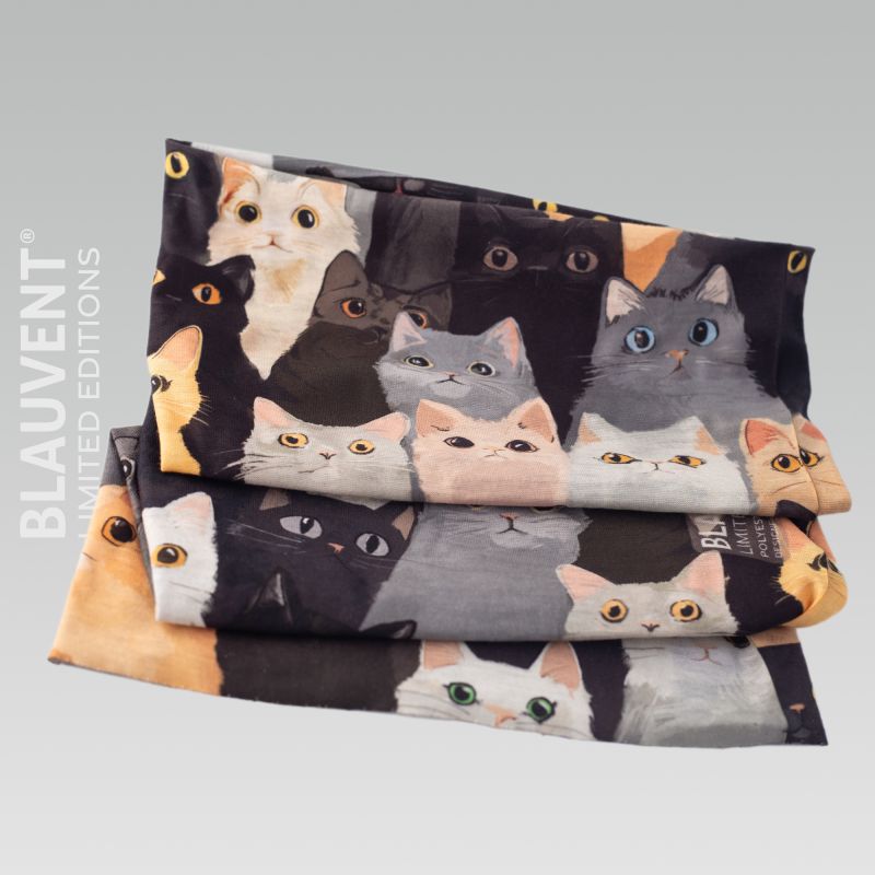 Folded multifunctional neckwarmer with a playful repeating illustration of cat faces.