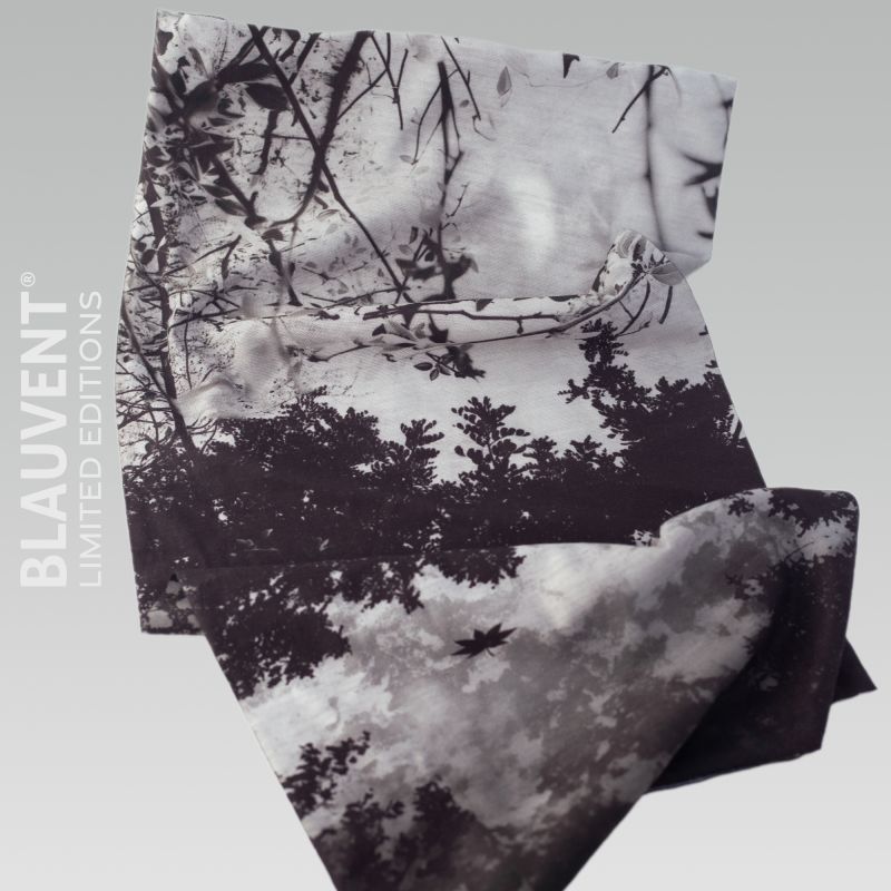 Flat view of a monochrome forest-print neckwarmer with silhouettes of trees and branches.